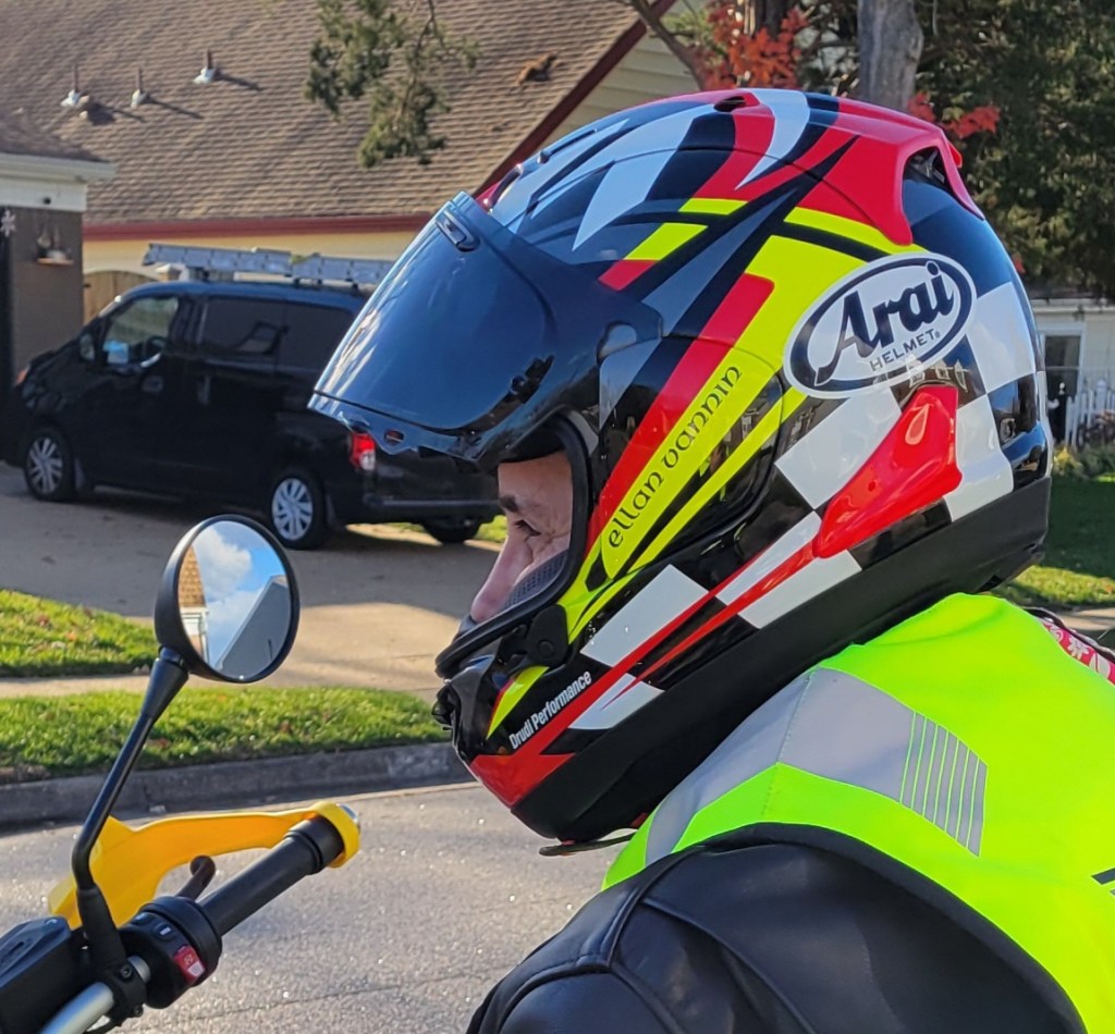 Arai motorcycle helmet in yellow, white, black, and red.