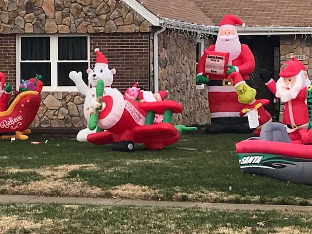 Christmas inflatables including a polar bear wearing a Santa hat and waving; Santa and two pigs in an airplane; a tall Santa; a Grinch; a Santa in row boat.