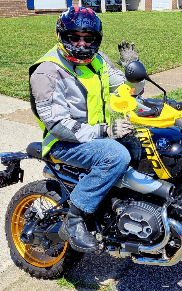author sitting on black and yellow motorcycle waving